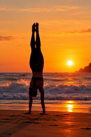 athlete performing a handstand on a beach