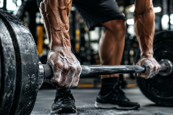 chalk covered hands gripping a heavy barbell